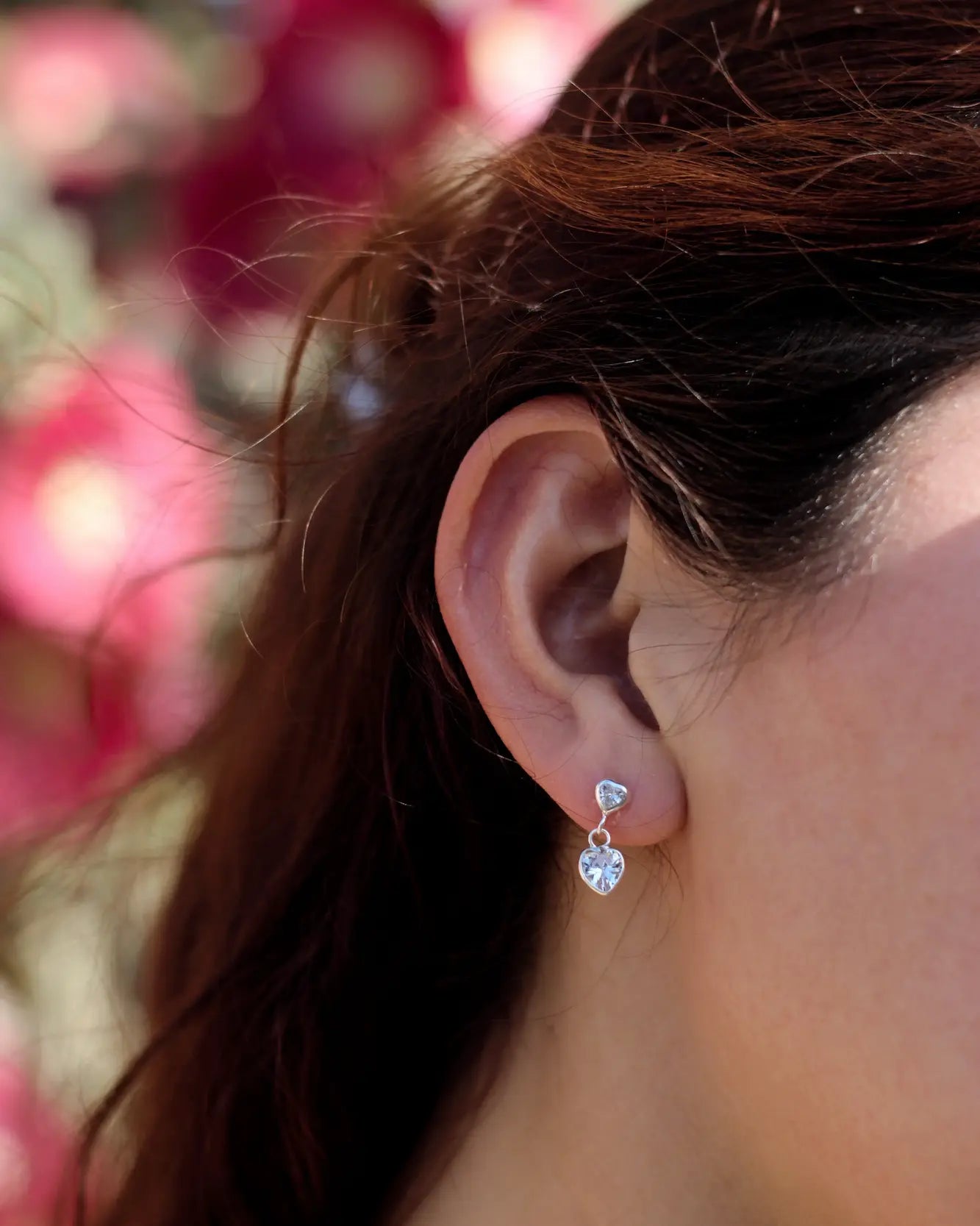 Modelo con aros con colgante de corazón blanco en plata 925, diseño elegante de Sylara.